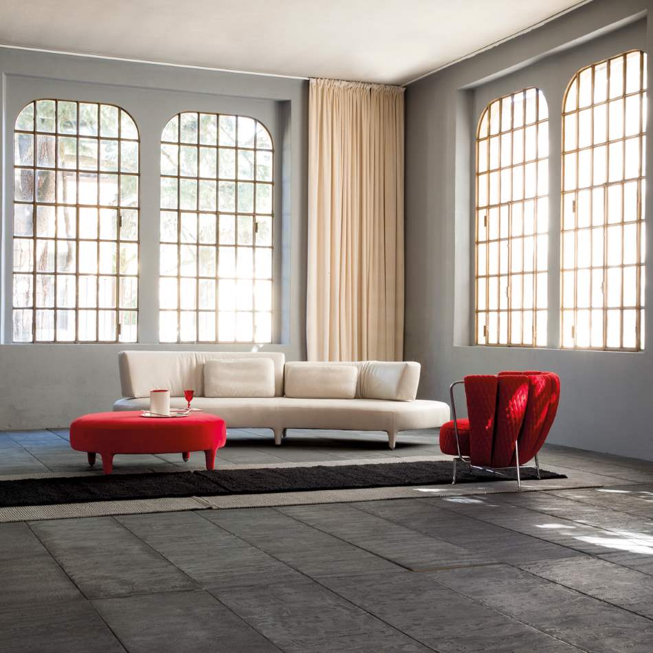 Delta Sagomato sofa with red foot stools nearby
