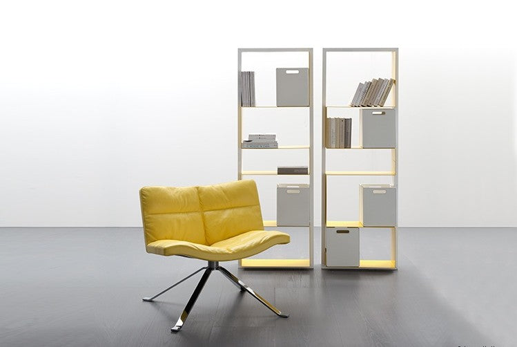 Wave Soft Chair in yellow leather with bookshelf behind it